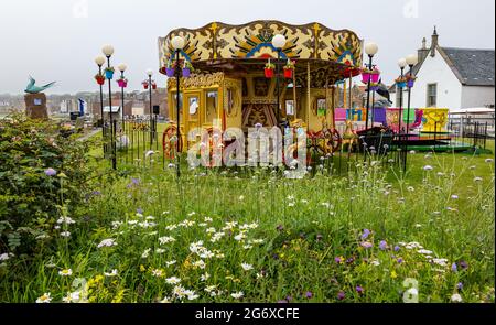 North Berwick, East Lothian, Schottland, Großbritannien. Juli 2021. UK Wetter: Neblig am Meer: Die Küstenstadt ist von haar oder Meeresnebel umgeben, mit wenigen Besuchern am Strand. Es ist warm und schwül. Im Bild: Das traditionelle Kinderkarussell Stockfoto