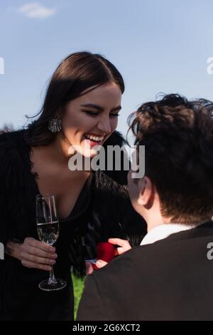 Mann, der eine glückliche Frau mit einem Glas Champagner anschlägt Stockfoto