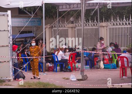 Phnom Penh, Kambodscha. 9. Juli 2021. Seit 4 Monaten kämpft Phnom Penh mit einem COVID - 19 Anstieg. Kambodschaner, die in schützenden Gesichtsmasken / -Abdeckungen, die positiv auf das Virus getestet haben, warten auf Krankenwagen, mit ihren Beuteln verpackt, an einer Massenteststelle. Eine kambodschanische Mutter wartet mit ihrer Tochter, die beide positiv getestet wurden. Kambodschaner, die positiv testen, können den Teststandort nicht verlassen und müssen einen Freund oder einen Verwandten anrufen, um ihre persönlichen Sachen für den 2-wöchigen Aufenthalt im Krankenhaus abzuholen. Quelle: Kraig lieb / Alamy Live News Stockfoto