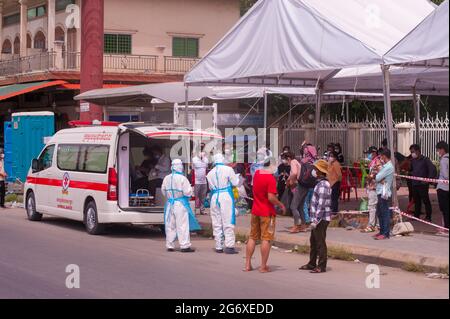 Phnom Penh, Kambodscha. 9. Juli 2021. Seit 4 Monaten kämpft Phnom Penh mit einem COVID - 19 Anstieg. Kambodschaner, in schützenden Gesichtsmasken / Abdeckungen, die positiv auf das Virus getestet haben, warten auf einen Krankenwagen, mit ihren Tüten verpackt, an einer Massenteststelle zu bekommen. 2 Notärzte/Sanitäter in voller PSA kontrollieren die Situation. Kambodschaner, die positiv testen, können den Teststandort nicht verlassen und müssen einen Freund oder einen Verwandten anrufen, um ihre persönlichen Sachen für den 2-wöchigen Aufenthalt im Krankenhaus abzuholen. Quelle: Kraig lieb / Alamy Live News Stockfoto