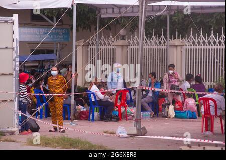 Phnom Penh, Kambodscha. 9. Juli 2021. Seit 4 Monaten kämpft Phnom Penh mit einem COVID - 19 Anstieg. Kambodschaner, die in schützenden Gesichtsmasken / -Abdeckungen, die positiv auf das Virus getestet haben, warten auf Krankenwagen, mit ihren Beuteln verpackt, an einer Massenteststelle. Eine kambodschanische Mutter wartet mit ihrer Tochter, die beide positiv getestet wurden. Kambodschaner, die positiv testen, können den Teststandort nicht verlassen und müssen einen Freund oder einen Verwandten anrufen, um ihre persönlichen Sachen für den 2-wöchigen Aufenthalt im Krankenhaus abzuholen. Quelle: Kraig lieb / Alamy Live News Stockfoto