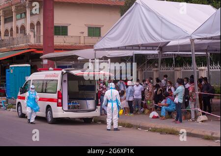 Phnom Penh, Kambodscha. 9. Juli 2021. Seit 4 Monaten kämpft Phnom Penh mit einem COVID - 19 Anstieg. Kambodschaner, in schützenden Gesichtsmasken / Abdeckungen, die positiv auf das Virus getestet haben, warten auf einen Krankenwagen, mit ihren Tüten verpackt, an einer Massenteststelle zu bekommen. 2 Notärzte/Sanitäter in voller PSA kontrollieren die Situation. Kambodschaner, die positiv testen, können den Teststandort nicht verlassen und müssen einen Freund oder einen Verwandten anrufen, um ihre persönlichen Sachen für den 2-wöchigen Aufenthalt im Krankenhaus abzuholen. Quelle: Kraig lieb / Alamy Live News Stockfoto