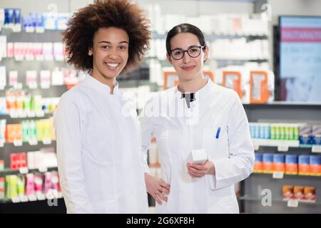 Porträt von zwei Apothekerinnen in weißen Laborkittel, während sie bei der Arbeit im Inneren einer modernen Drogerie mit verschiedenen p Stockfoto