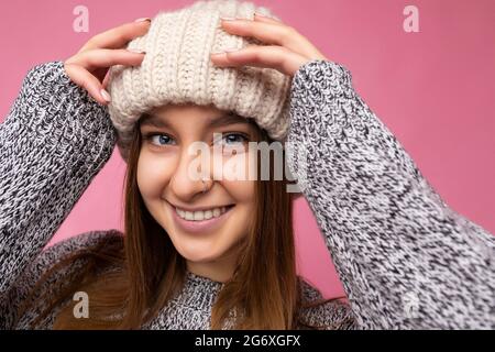 Nahaufnahme eines ziemlich fröhlich lächelnden jungen dunkelblonden weiblichen Menschen, der isoliert über einer farbenfrohen Hintergrundwand steht und trendige Alltagskleidung trägt Stockfoto