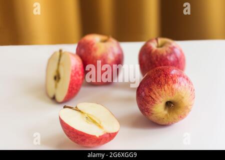 Äpfel auf einem weißen Tisch über einem gelben Vorhang, horizontal Stockfoto