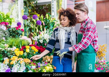 Schöne Lateinamerikanischen Frau kaufen Freesien an den Rat eines Hilfsbereit und stattlichen Anbieter in einer modernen Flower Shop Stockfoto