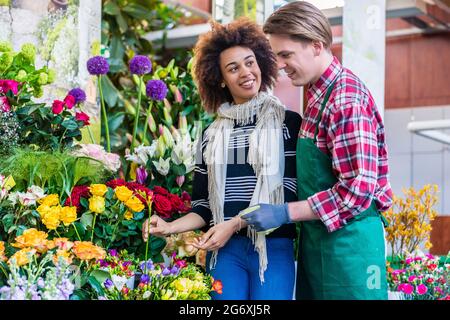 Schöne Lateinamerikanischen Frau kaufen Freesien an den Rat eines Hilfsbereit und stattlichen Anbieter in einer modernen Flower Shop Stockfoto