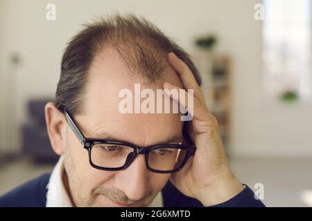 Nahaufnahme sorgte sich reifer Geschäftsmann, der den Kopf mit der Hand hielt und enttäuscht aussagte Stockfoto