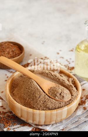 Schüssel mit rohen Leinsamen Mehl und Samen mit einem Löffel schließen auf weißem Tisch Stockfoto