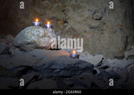 Drei Teelichtkerzen auf Felsen in einer Höhle Stockfoto