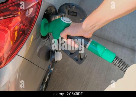 Die Hände des Mannes halten die Gaspumpe und füllen das Auto mit Kraftstoff aus nächster Nähe. Energiewirtschaft. Tankstellengeschäft/Markt. Stockfoto