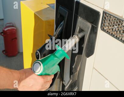 Die Hand des Mannes nimmt die Düse der grünen Gaspumpe an der Tankstelle aus der Nähe. Gasindustrie/-Markt. Energie. Tankstellenbetrieb. Stockfoto