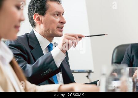 Seitenansicht eines fachkundigen Geschäftsmannes, der während eines Entscheidungstreffens in der Konferenz seine Meinung über die Entwicklung eines wichtigen Projekts teilt Stockfoto