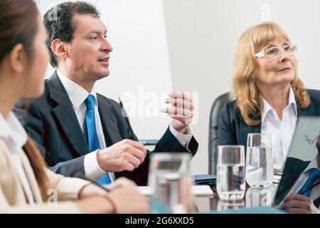 Seitenansicht eines fachkundigen Geschäftsmannes, der während eines Entscheidungstreffens in der Konferenz seine Meinung über die Entwicklung eines wichtigen Projekts teilt Stockfoto