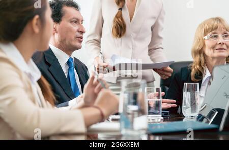 Seitenansicht eines hochqualifizierten Managers in hispanischer Mitte, der mit seinen Kollegen zusammenarbeitet, um während eines Meetings im Konferenzraum Lösungen zu finden Stockfoto