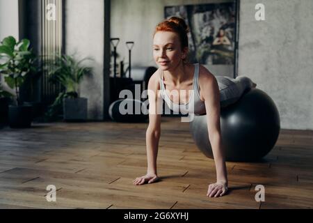 Fit Frau balanciert auf Gymnastikball im Fitnessstudio während Pilates Training Stockfoto