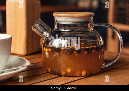 Tee mit Sanddorn in Glas Teekannen im Café - Bild Stockfoto