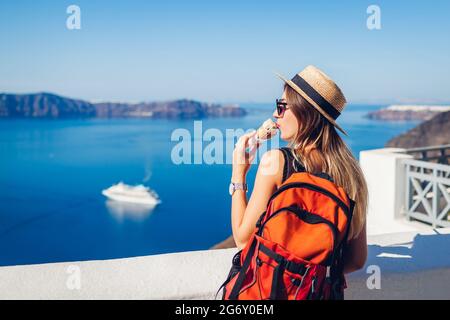 Frau Reisende essen Eis in Fira Santorini Insel auf Caldera Meer Hintergrund genießen Landschaft. Essen im Sommer. Stockfoto
