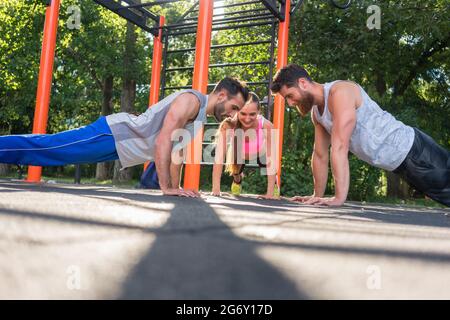 Zwei passen junge Männer klatschen Hände vom Gesicht Ganzkörperstütz während Partner Training durch ihren Freund draußen im Park motiviert zu Gesicht Stockfoto