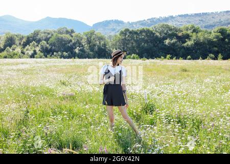 Schöne Frau in Kleid Spaziergänge auf dem Feld der Gänseblümchen Stockfoto