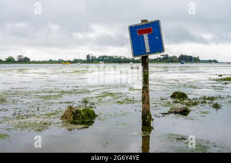 Kein Durchgangsschild auf einer überfluteten Straße bei Flut, wo die Straße regelmäßig in Bosham, West Sussex, England, Großbritannien, überflutet wird. Stockfoto