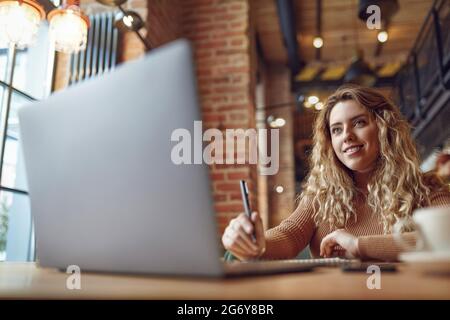 Frau, die am Laptop arbeitet und sich Notizen gemacht hat Stockfoto