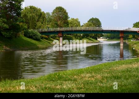 Kleine Brücke über den Fluss mit Bäumen und Gras im Sommer Stockfoto