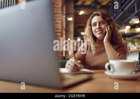 Angenehme Frau, die in Innenräumen mobile Gespräche führt Stockfoto