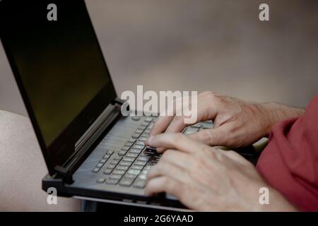 Detail der Hände des Mannes auf der Laptop-Tastatur im Freien Stockfoto