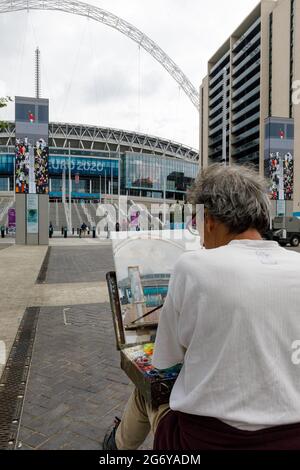 Wembley Stadium, Wembley Park, Großbritannien. Juli 2021. Der Wembley Park ist vor dem Spiel am Sonntag voller Aufregung. Der in London lebende Künstler Nick Botting, der zuvor mit der Bemalung des FA Cup Finales beauftragt wurde, sitzt auf dem Olympic Way und malt das Wembley Stadium, um ein Kunstwerk dieses historischen Anlasses zu schaffen. 60,000 Fans werden am Sonntag, den 11. Juli, im Wembley-Stadion im Wembley-Stadion in Italien beim UEFA EURO 2020-Finale spielen. Amanda Rose/Alamy Live News Stockfoto