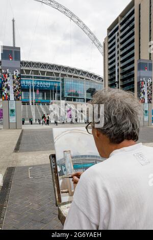 Wembley Stadium, Wembley Park, Großbritannien. Juli 2021. Der Wembley Park ist vor dem Spiel am Sonntag voller Aufregung. Der in London lebende Künstler Nick Botting, der zuvor mit der Bemalung des FA Cup Finales beauftragt wurde, sitzt auf dem Olympic Way und malt das Wembley Stadium, um ein Kunstwerk dieses historischen Anlasses zu schaffen. 60,000 Fans werden am Sonntag, den 11. Juli, im Wembley-Stadion im Wembley-Stadion in Italien beim UEFA EURO 2020-Finale spielen. Amanda Rose/Alamy Live News Stockfoto