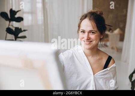 Porträt einer lächelnden Frau, die im Kunststudio malt Stockfoto