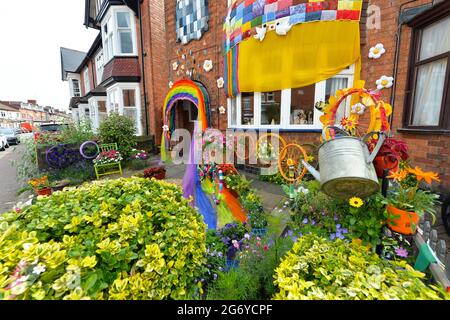 Leicester, Leicestershire, Großbritannien, 9. Juli 2021. UK News. Die Mixed-Media-Künstlerin Alison Zimmerer-Hughes mit ihrer Kunstinstallation ‘Blooming Lovely“ vor ihrem Haus in Aylestone, Leicester. Die Mischung von Textilien und Blumen bringt Farbe und Natur in die Stadt. Das Kunstwerk wurde von Vehicle Arts für das ‘Projekt „Up Your Street“ in auftrag gegeben. Da es im letzten Jahr so einen Mangel an Zugang zu den Künsten gab, ist die Prämisse des Projekts, die Straßen in der Umgebung zu erhellen und die Menschen zu engagieren. Quelle: Alex Hannam/Alamy Live News Stockfoto