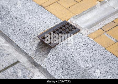 Drainage-System Rost, Grill für die Entfernung von Regenwasser von Wanderwegen durch Graben und Loch in Granit Curbe auf der Straße Engineering-Strukturen cl Stockfoto