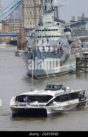 London, England, Großbritannien. Uber Boat / Thames Clipper, nahe der HMS Belfast, Tower Bridge im Hintergrund Stockfoto