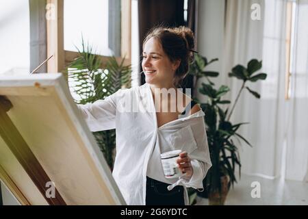 Lächelnde Malerin, die auf Staffelei zeichnet Stockfoto