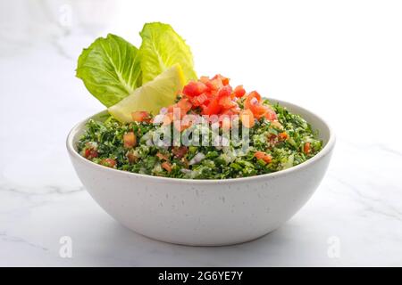Traditioneller arabischer Salat tabbouleh, isoliert auf Marmorkulisse Stockfoto