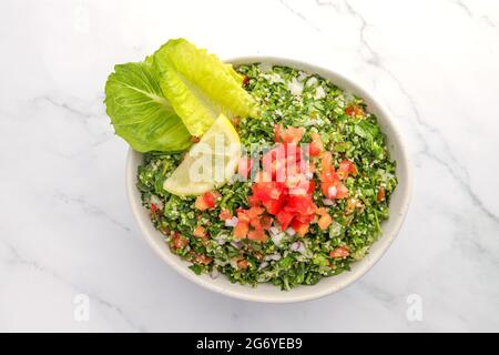 Traditioneller arabischer Salat tabbouleh, isoliert auf Marmorkulisse Stockfoto