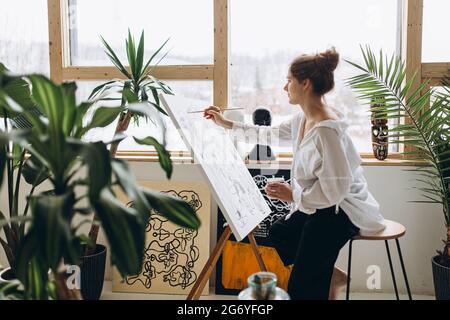 Künstlerin zeichnet abstraktes Bild auf Staffelei Stockfoto