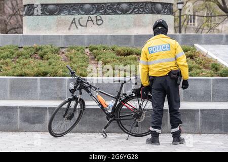 Ein Polizist steht vor Anti-Polizei-ACAB-Graffiti („All Cops are Bastards“) im Queen's Park, Toronto. Stockfoto