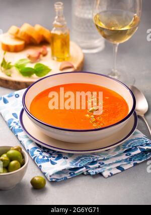 Traditionelles spanisches Gericht. Kalte, vegetarische Suppe aus Tomaten, Paprika, Knoblauch und Olivenöl mit Tabasco-Sauce auf einem weißen Teller auf einer Serviette. Weiß w Stockfoto