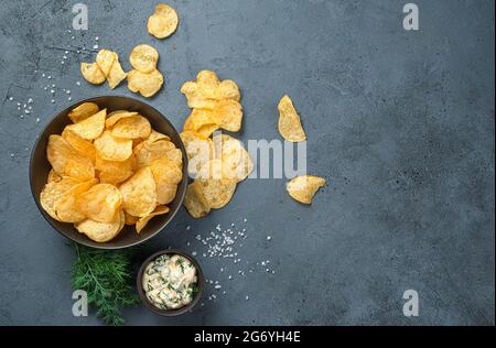 Kartoffelchips mit Sauerrahm und Dill auf dunkelgrauem Hintergrund. Stockfoto