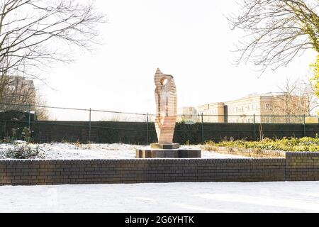 Die Clothier-Skulptur von John Atkin, viele Bäume und Hecken. Ein neuer Spaziergang geht über, mit Waterloo Way im Hintergrund. Helle Sonne und Himmel. Stockfoto