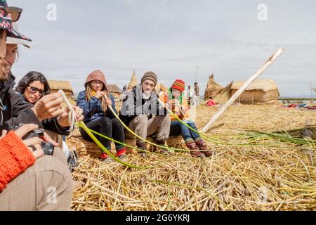 TITICACA, PERU - 15. MAI 2015: Besucher erfahren mehr über das Schilf, das für den Bau von schwimmenden Uros-Inseln, dem Titicacasee, Peru, verwendet wird Stockfoto