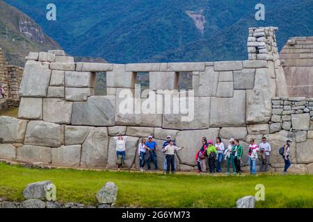 MACHU PICCHU, PERU - 18. MAI 2015: Touristen vor dem Tmple der drei Fenster in den Machu Picchu Ruinen, Peru. Stockfoto