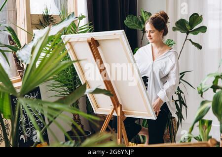 Frau malt auf Staffelei im Studio Stockfoto