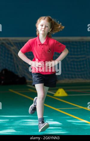 Grundschule Mädchen Kind / Kind nimmt am Schulsporttag am Rennsport Teil, leiden Stichschmerzen, am Ende des akademischen Jahres & Schulzeit. Stockfoto