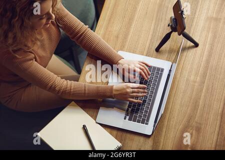 Hübsche Frau, die auf dem Laptop tippt, während sie im Café sitzt Stockfoto