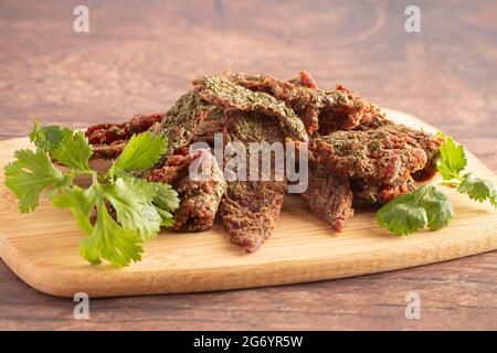 Gourmet Cilantro Flavored Beef Jerky auf einem Holzschneidebrettchen Stockfoto