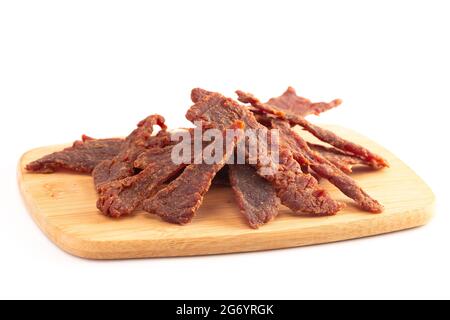 Streifen von Beef Jerky auf einem Schneidbrett isoliert auf einem weißen Hintergrund Stockfoto